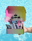NightCap Gift Box featuring reusable drink spiking prevention scrunchies, keychain, bottle tops, keychain straw, shot glass, and stickers in gift-ready packaging.